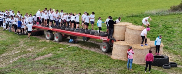 Vue aérienne de participants franchissant un parcours d'obstacles fait de pneus et de bottes de paille